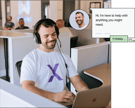A man smiles at his open cubicle, he types on his laptop computer that he’s here to help with anything they might need